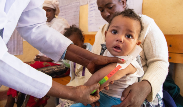 A community health worker measures an infant’s mid-upper arm circumference to screen for malnutrition
